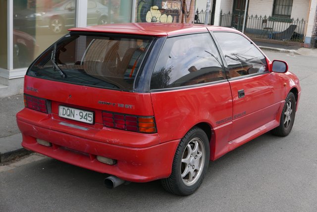 Rear three-quarter period reference of the same red 1989 Suzuki Swift GTi, showing its hatch, window line and tail lamps.